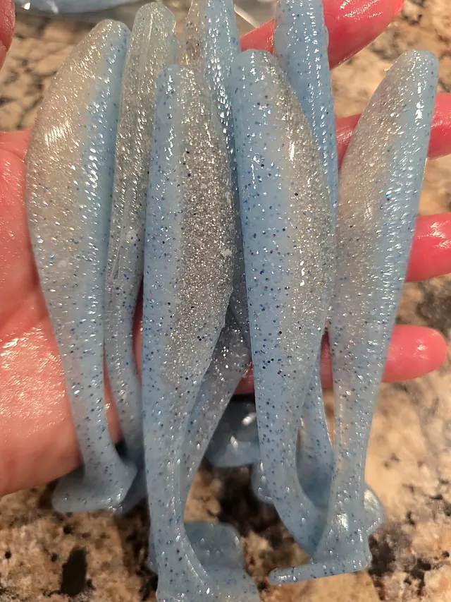 A handful of pale blue paddle tail swimbaits with silver flake